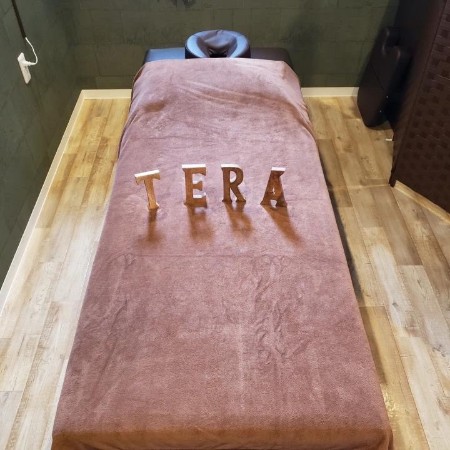 「もみほぐし手楽（てら）」のイメージ写真。施術用のベッドの上に「TERA」のアルファベットの模型が並んでします。